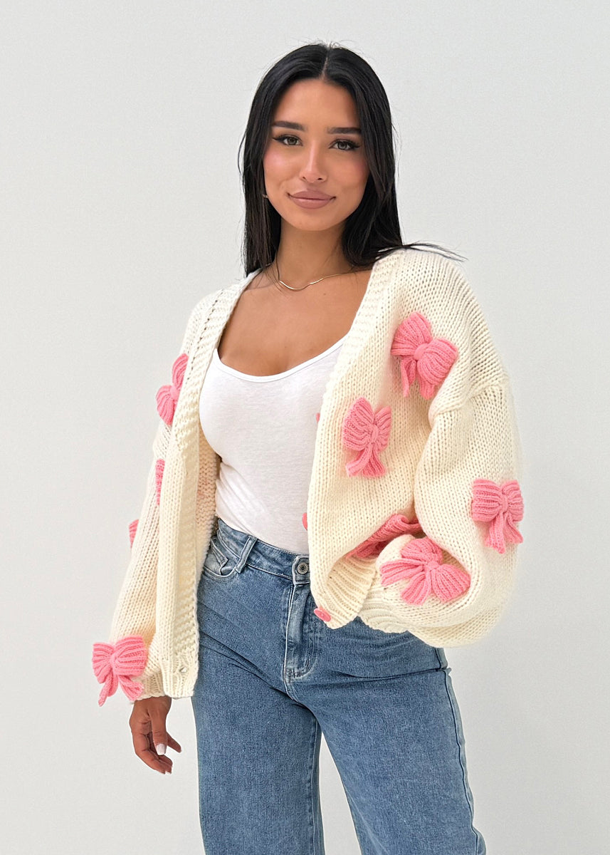 Modell trägt eine verspielte Damen Strickjacke mit aufgesetzten Strickschleifen – NAHA Fashion