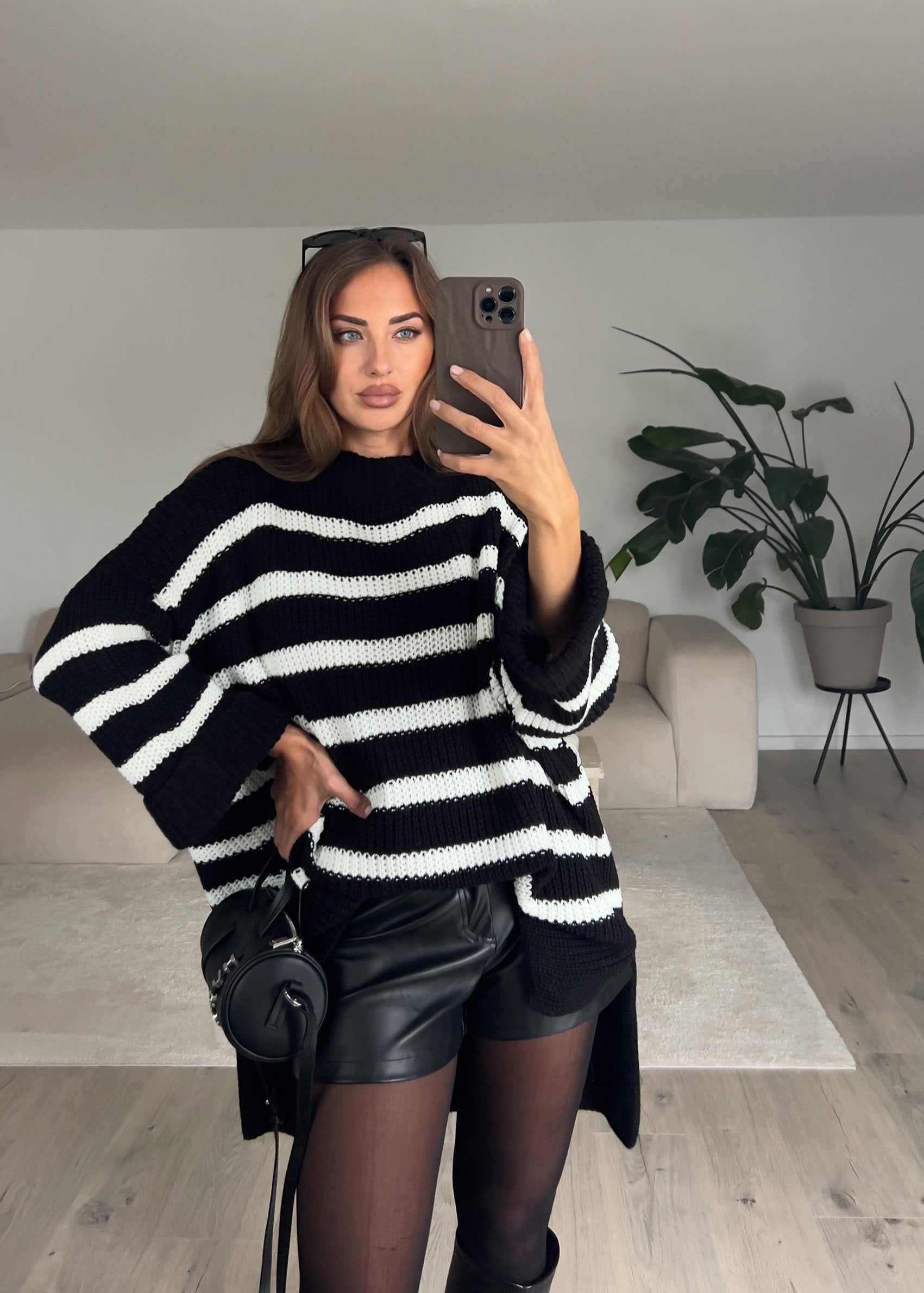 Modell trägt einen schwarz-weiß gestreiften Strickpullover mit geradem Schnitt und Rundhalsausschnitt