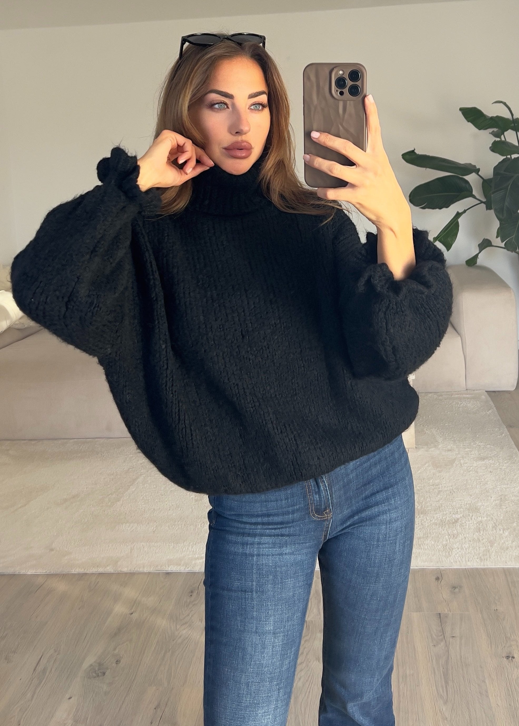 Modell trägt einen schwarzen Rollkragenpullover mit geradem Schnitt und weichem Strick